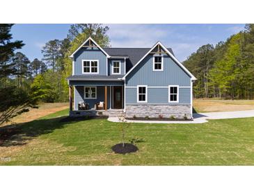 Charming two-story home with blue siding, stone accents and manicured lawn and craftsman details at 123 Wichita Way, Louisburg, NC 27549