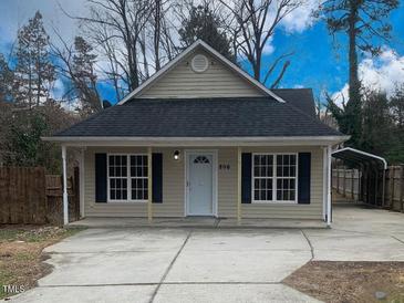 Beige house with gray roof, covered parking, and a fenced yard at 806 Piper St, Durham, NC 27704
