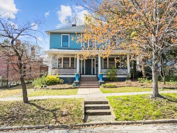Charming two-story blue home featuring a welcoming front porch and beautiful landscaping at 417 Elm St, Raleigh, NC 27604