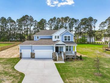 Two-story home featuring a manicured lawn, a three car garage, and a charming front porch at 155 Shelby Meadow Ln, Angier, NC 27501
