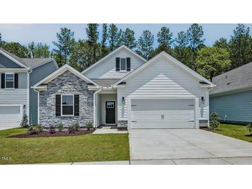 Charming home featuring stone accents, white siding, a two-car garage, and well-manicured lawn at 7529 Percussion Dr, Apex, NC 27539