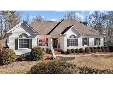 White two-story house with a brown roof, landscaping, and a large front yard at 319 Fox Hollow Dr, Clayton, NC 27527