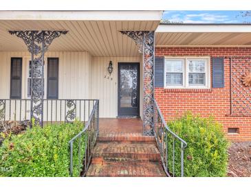 Charming brick home featuring a cozy front porch with decorative iron railings and steps at 229 Davis Mill Rd, Selma, NC 27576