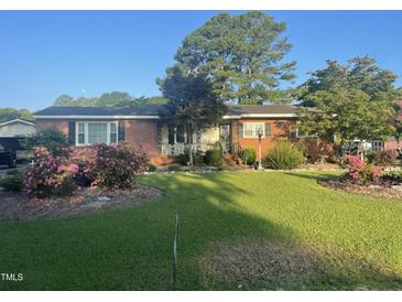 Charming brick home featuring mature landscaping and a well-manicured lawn at 229 Davis Mill Rd, Selma, NC 27576
