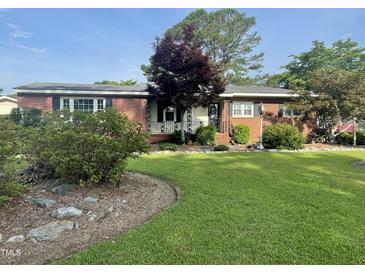 Charming brick home featuring a well-manicured lawn and mature landscaping at 229 Davis Mill Rd, Selma, NC 27576
