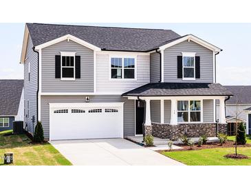 Charming two-story home featuring a two-car garage, stone accents, and a welcoming front porch at 59 Davinhall Dr, Fuquay Varina, NC 27526