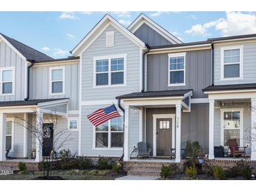 Charming townhouse featuring a covered porch, American flag, and two-tone gray siding at 728 Silo Park Dr, Wake Forest, NC 27587