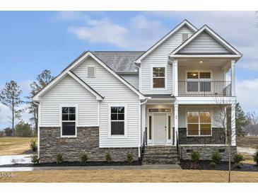 Charming two-story home boasts white siding, stone accents, covered balcony, and inviting front porch at 89 Jumper St, Wendell, NC 27591