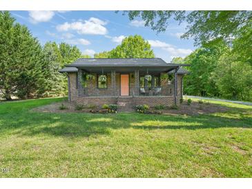 Charming brick home featuring a covered front porch, landscaped front yard, and beautiful curb appeal at 320 W Orange St, Hillsborough, NC 27278