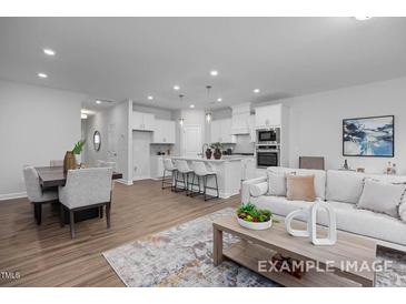 Open-concept living room boasts an island kitchen, dining area and comfortable seating at 3934 Well Fleet Drive, Fuquay Varina, NC 27526