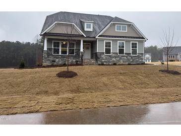 Charming home featuring stone accents, a covered porch, and a freshly installed lawn at 200 Ironwood Lot 39 Blvd, Youngsville, NC 27596