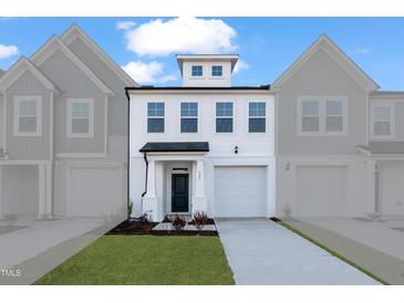 Charming new construction townhome features a white exterior with a one car garage and a well manicured lawn at 527 Eversden Dr, Zebulon, NC 27597