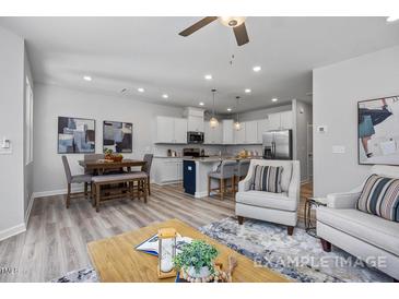 Open-concept living room features modern decor, ceiling fan, and a view of the kitchen at 3928 Well Fleet Drive, Fuquay Varina, NC 27526