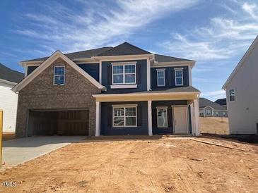 Charming two-story home featuring a brick and blue facade, a covered porch, and an attached two-car garage at 319 N Maple Walk # 213, Garner, NC 27529