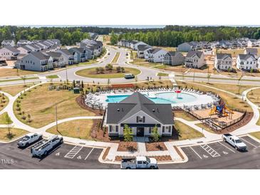 Community clubhouse featuring a pool, lounge chairs, playground, and parking at 921 Jasper Mine Trl, Raleigh, NC 27610