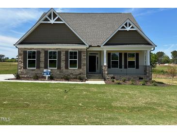 Charming home featuring stone accents, a covered porch, and beautifully landscaped front yard at 243 Kissington Way, Benson, NC 27504
