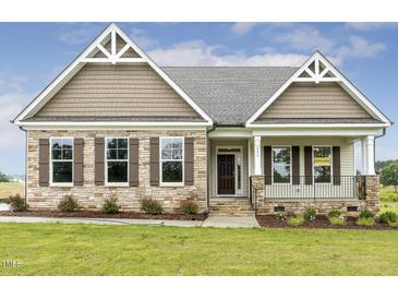 Charming single-story home with stone accents, manicured lawn, and inviting front porch at 243 Kissington Way, Benson, NC 27504