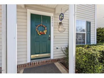 Inviting green front door with wreath, brick walkway, and well-manicured shrubs at 2248 Ventana Ln, Raleigh, NC 27604