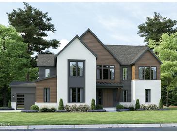 Modern two-story home with a mix of brick and wood siding, a large garage, and landscaping at 3705 Joyful Creek Trl, Zebulon, NC 27597
