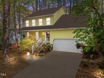 Charming yellow two-story home with a well-manicured lawn and inviting front porch and attached two car garage at 102 Pinehill Way, Cary, NC 27513