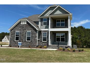 Beautiful two-story home featuring stone accents, a covered porch, and manicured landscaping at 85 Kissington Way, Benson, NC 27504