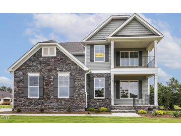 Attractive two-story home with gray siding, stone accents, and a welcoming double stacked front porch at 85 Kissington Way, Benson, NC 27504