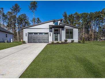 Modern home featuring sleek gray siding, a gray garage door, and well-manicured lawn at 145 Ottawa Dr, Louisburg, NC 27549