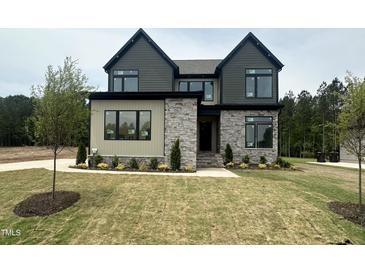 New construction featuring a stone and siding facade, complemented by a lush green lawn and manicured landscaping at 135 Cherry Bark Dr, Youngsville, NC 27596