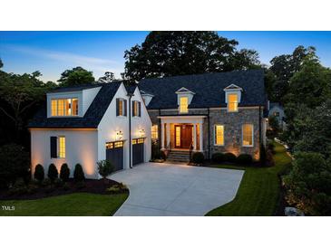 Elegant stone and white two-story home featuring a manicured lawn, dark roof, and attached garage at 1307 Mayfair Rd, Raleigh, NC 27608