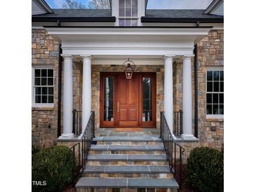 Elegant stone home featuring a covered front door with pillars, wooden door and glass sidelights at 1307 Mayfair Rd, Raleigh, NC 27608