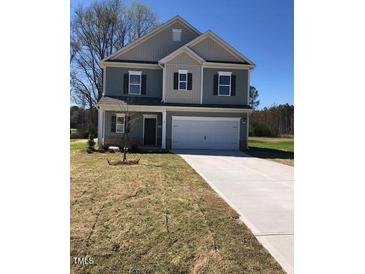 Two-story home featuring a two-car garage and neutral siding, located on a grassy lawn at 65 Vili Dr, Broadway, NC 27505