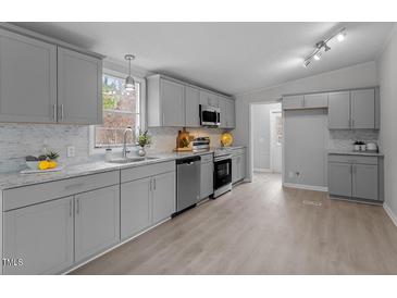 Updated kitchen featuring granite countertops, stainless steel appliances, gray cabinetry, and tiled backsplash at 97 Brent Wood Ct, Sanford, NC 27332