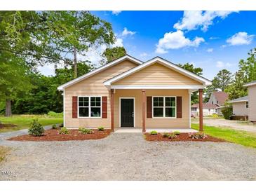 New construction home with tan siding, landscaping, and a covered porch at 157 Rainbow Dr, Dunn, NC 28334