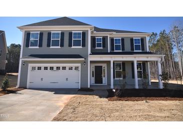 Charming two-story home featuring a two-car garage, covered front porch, and well-manicured lawn at 60 Accord Dr, Youngsville, NC 27596