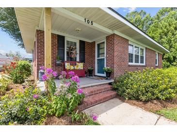 Inviting front porch with brick steps, red bench, and blooming flowers at 105 W Ivey St, Lillington, NC 27546