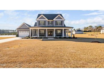 Two-story farmhouse with gray siding, porch, and large yard at 108 Waterfall Dr, Sanford, NC 27330