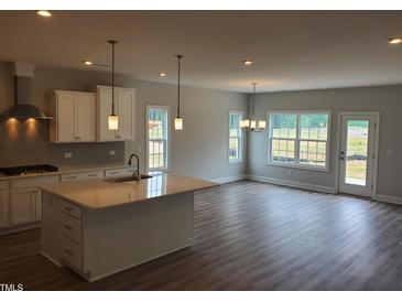 Open-concept kitchen featuring a large island, modern pendant lights, and stainless steel appliances at 308 Whispering Way, Sanford, NC 27330
