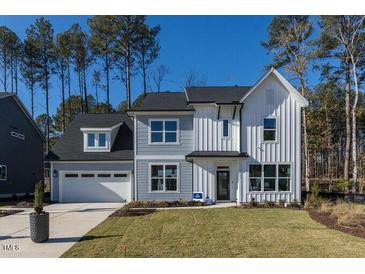 Two-story home with gray and white siding, and a three-car garage at 3395 Mission Olive Pl, New Hill, NC 27562