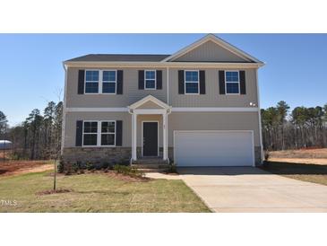 Charming two-story home featuring neutral siding, stone accents, a two-car garage, and a well-manicured front lawn at 45 Calabria Ct, Franklinton, NC 27525