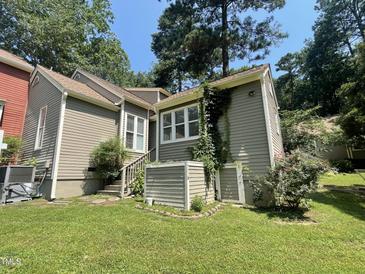 Charming home exterior featuring neutral siding, mature trees, and manicured lawn at 5718 Sentinel Dr, Raleigh, NC 27609
