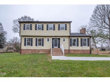 Two-story house with brick and siding, featuring a front porch and landscaped lawn at 802 S Sellars Mill Rd, Burlington, NC 27217