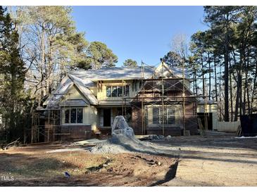 New construction home featuring a brick and siding facade, surrounded by scaffolding and construction materials at 8604 Windjammer Dr, Raleigh, NC 27615