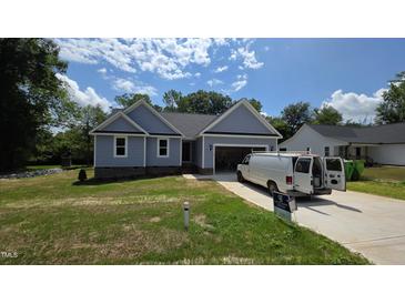 Charming single-story home with light blue siding and an attached garage on a sunny day at 121 Tanglewood Dr # 8-J, Louisburg, NC 27549