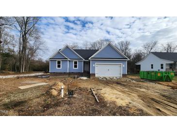 Newly constructed home with blue siding, a two-car garage, and a partially landscaped yard at 121 Tanglewood Dr # 8-J, Louisburg, NC 27549