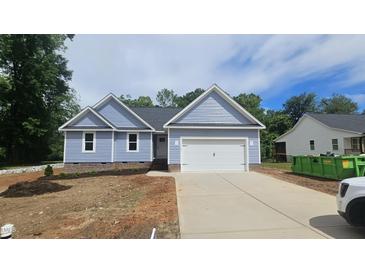 Charming single-story home with light blue siding, black roof, and a two car attached garage at 121 Tanglewood Dr # 8-J, Louisburg, NC 27549