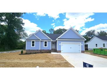 Charming one-story home with blue siding, a two-car garage, and a well-maintained lawn on a sunny day at 121 Tanglewood Dr # 8-J, Louisburg, NC 27549