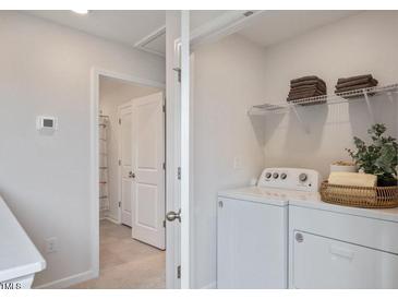 Bright laundry room with washer, dryer, and shelving at 440 Belgian Red Way, Wake Forest, NC 27587