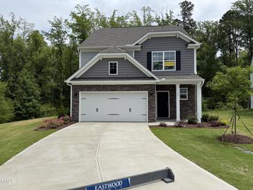 Charming two-story home boasts stone accents, a two-car garage, and a welcoming front yard at 137 Stallion Way, Benson, NC 27504