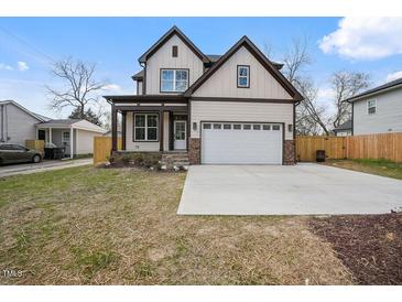Charming two-story home featuring light siding, dark trim, covered porch, and an attached two-car garage at 112 1St St, Oxford, NC 27565