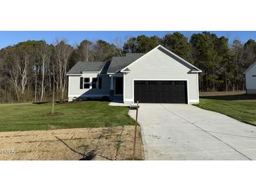 Newly constructed home with a gray exterior, black garage door, and a well-manicured lawn at 120 Magnolia Run Way, Benson, NC 27504